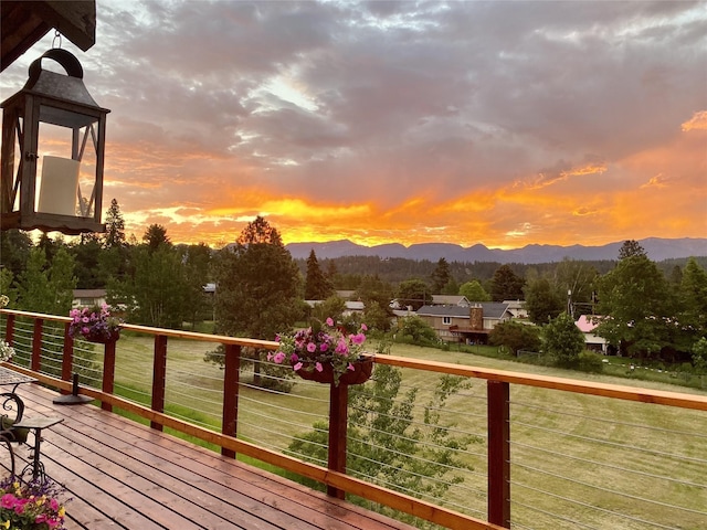 deck at dusk with a mountain view and a lawn