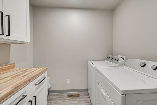 laundry area featuring cabinets, light hardwood / wood-style floors, and independent washer and dryer