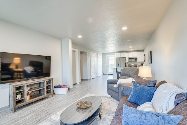 living room with a textured ceiling and light wood-type flooring