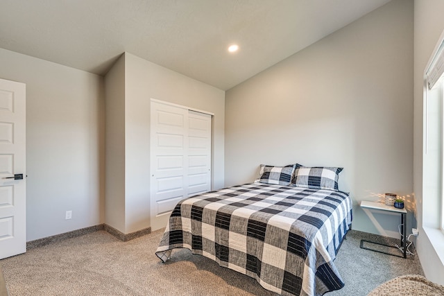 bedroom featuring light colored carpet, lofted ceiling, and a closet