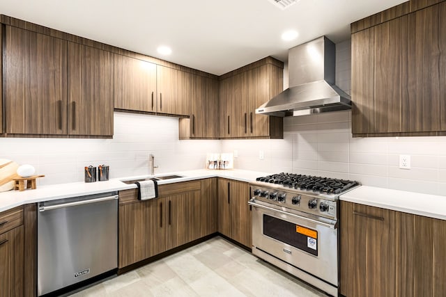 kitchen with stainless steel appliances, tasteful backsplash, sink, and wall chimney range hood