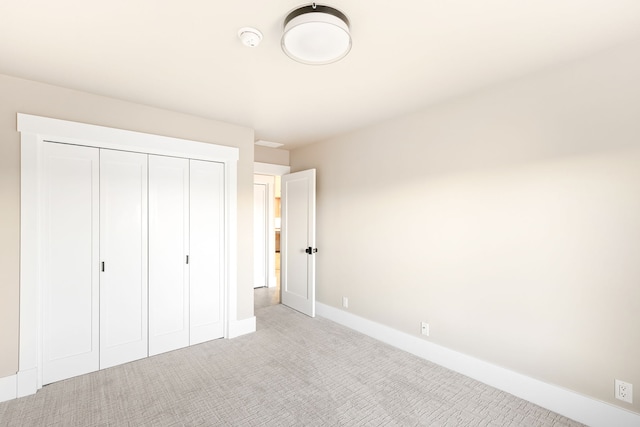 unfurnished bedroom with light colored carpet and a closet