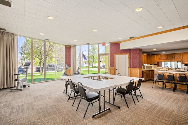 dining space with light colored carpet and a wall of windows