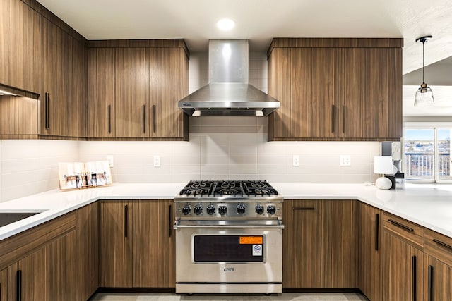 kitchen featuring decorative light fixtures, wall chimney range hood, decorative backsplash, and designer stove