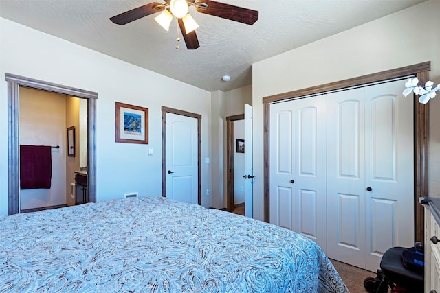 carpeted bedroom with ceiling fan, a closet, a textured ceiling, and ensuite bathroom