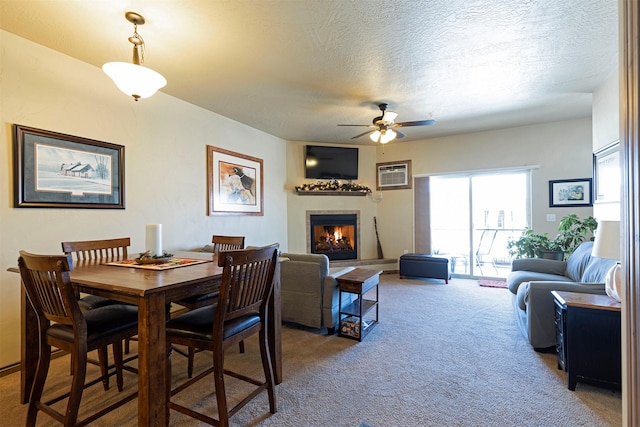 dining space featuring ceiling fan, carpet floors, a wall unit AC, and a textured ceiling