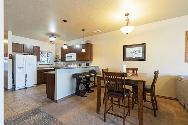 kitchen featuring hanging light fixtures, white appliances, kitchen peninsula, and a breakfast bar