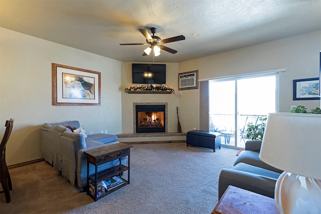 living room with an AC wall unit, a fireplace, carpet floors, ceiling fan, and a textured ceiling