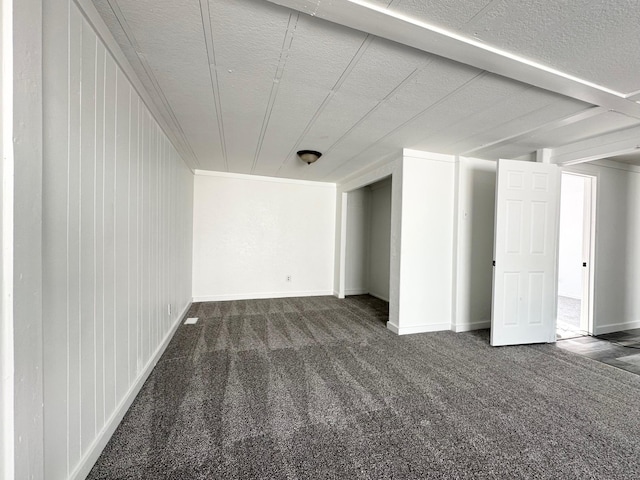 basement featuring dark carpet and a textured ceiling