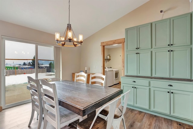 dining area with lofted ceiling, a notable chandelier, light hardwood / wood-style flooring, and washing machine and dryer