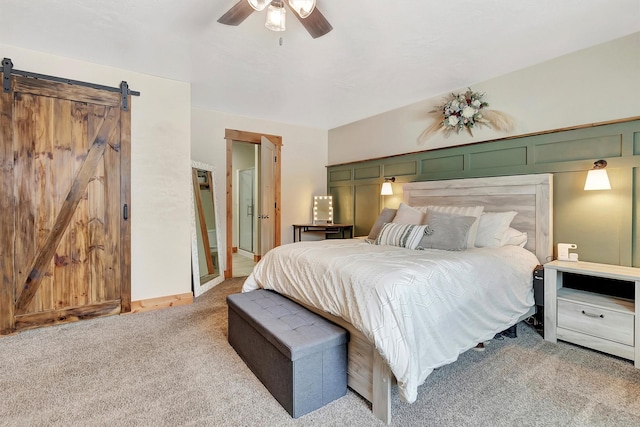 carpeted bedroom with a barn door and ceiling fan