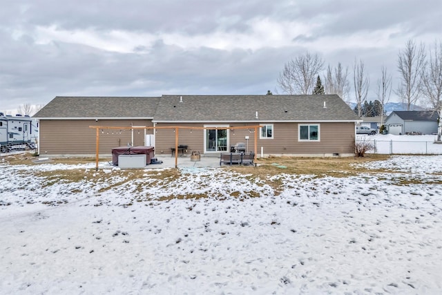 snow covered rear of property with a hot tub