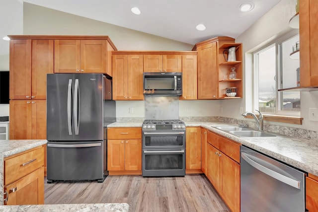 kitchen featuring lofted ceiling, appliances with stainless steel finishes, light hardwood / wood-style floors, and sink