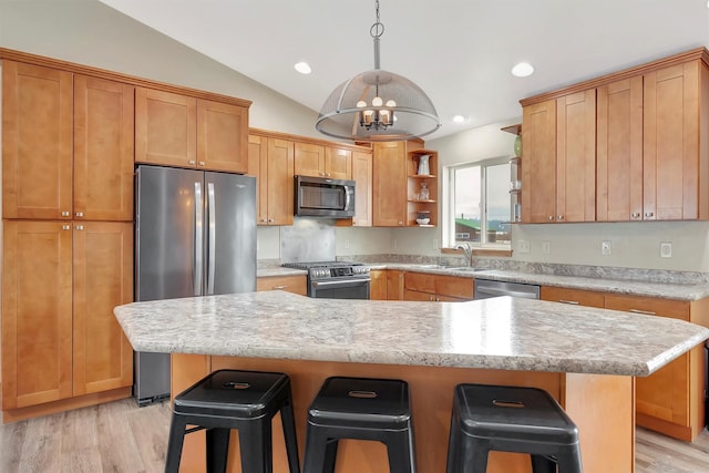 kitchen with sink, a breakfast bar, appliances with stainless steel finishes, a center island, and light hardwood / wood-style floors