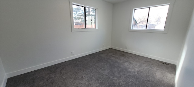 unfurnished room featuring dark carpet