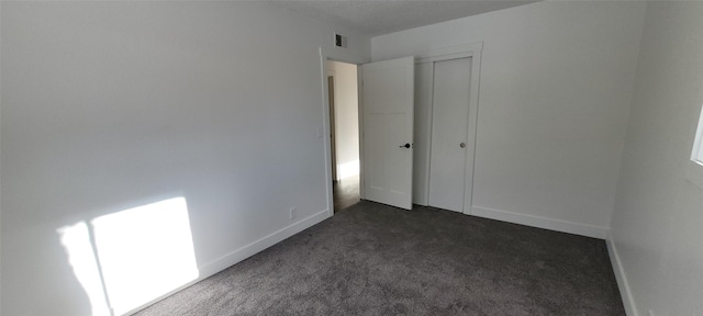 unfurnished bedroom featuring a closet and dark colored carpet