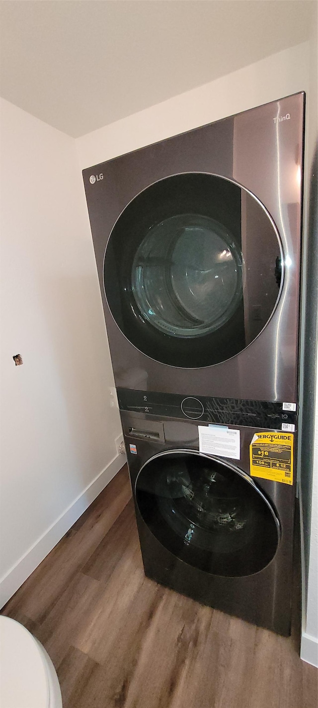 laundry area with hardwood / wood-style flooring and stacked washer and clothes dryer