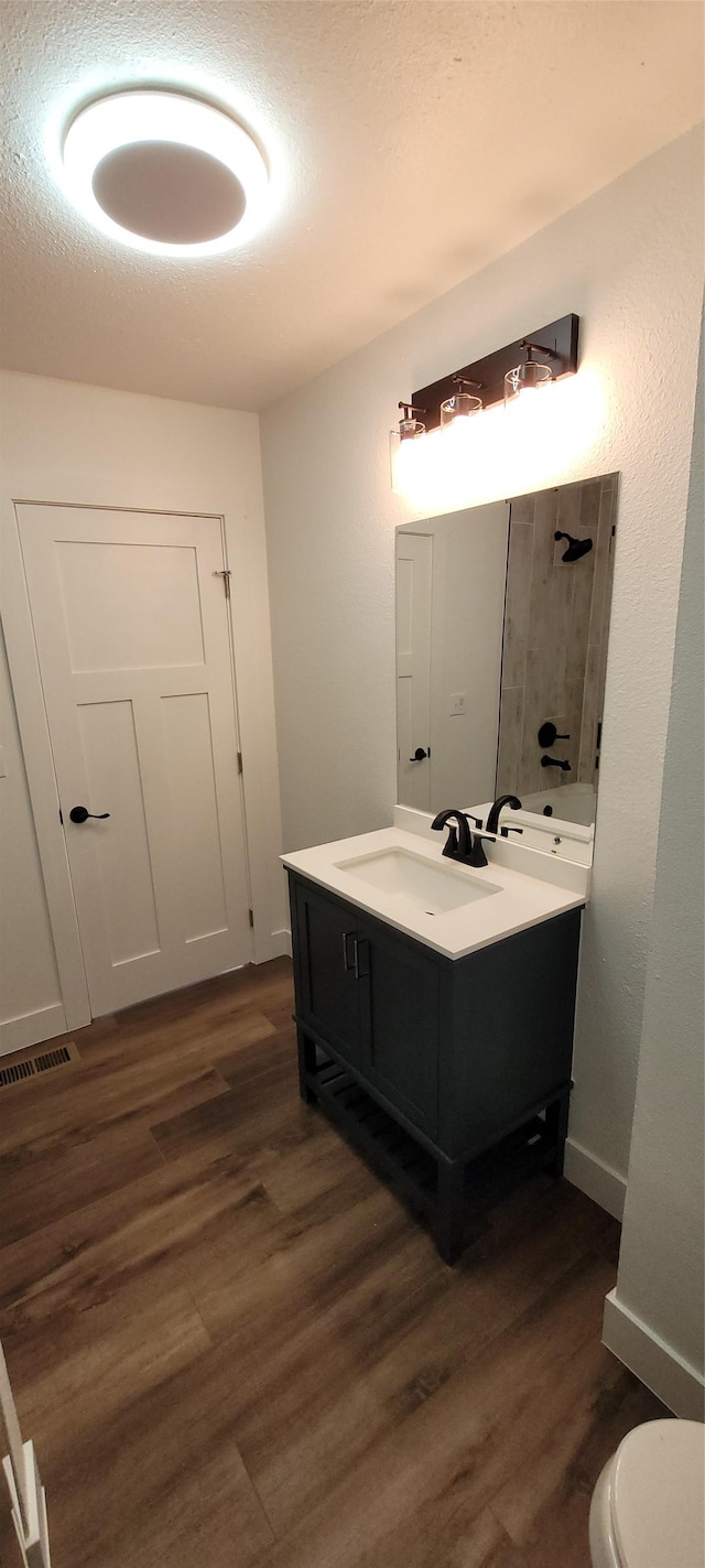 bathroom with hardwood / wood-style flooring, vanity, toilet, and a textured ceiling