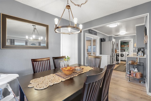 dining space with an inviting chandelier, washing machine and clothes dryer, light hardwood / wood-style flooring, and a textured ceiling