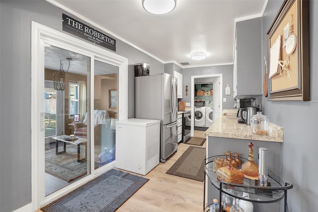 kitchen with separate washer and dryer, stainless steel fridge, fridge, light hardwood / wood-style floors, and crown molding