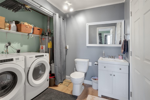 laundry room featuring water heater, sink, light hardwood / wood-style floors, and washer and dryer