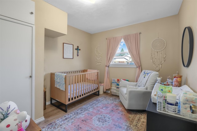 bedroom with a nursery area and wood-type flooring