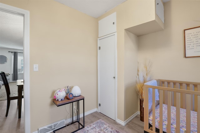 bedroom with a crib and light hardwood / wood-style flooring