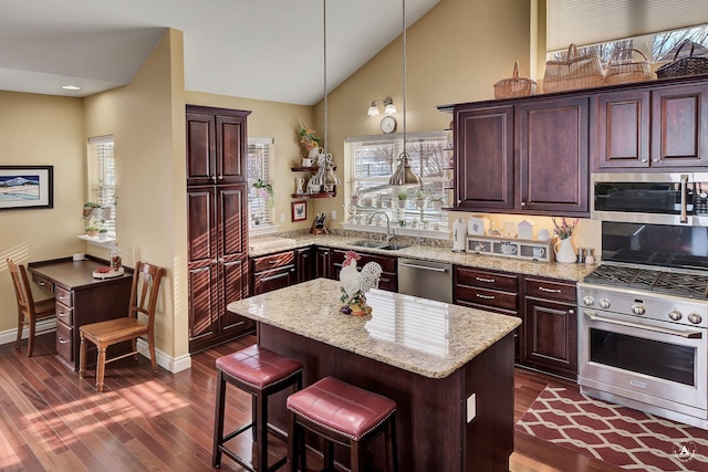 kitchen with lofted ceiling, sink, hanging light fixtures, appliances with stainless steel finishes, and a kitchen island