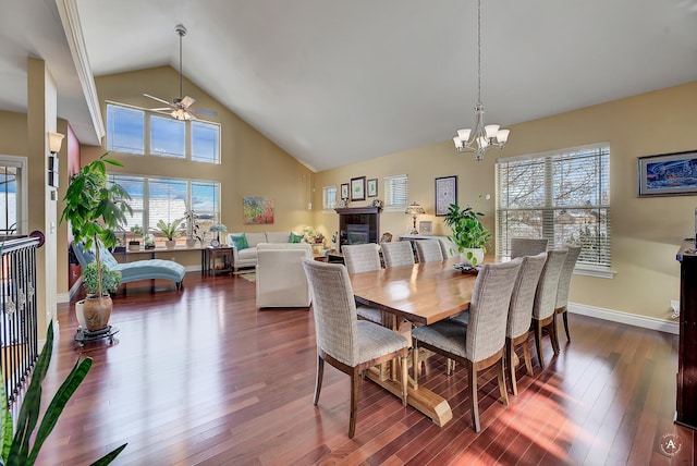 dining room featuring wood-type flooring, a healthy amount of sunlight, ceiling fan with notable chandelier, and high vaulted ceiling