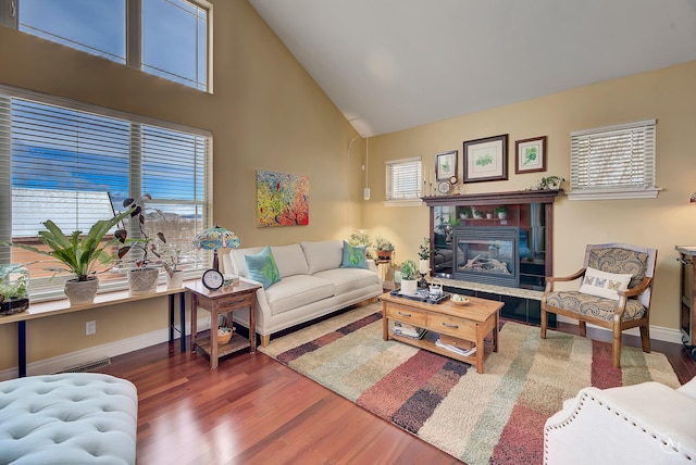 living room featuring dark hardwood / wood-style flooring, a tiled fireplace, and high vaulted ceiling