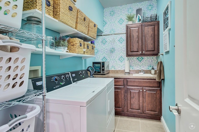 laundry room with sink, washing machine and dryer, cabinets, and light tile patterned flooring