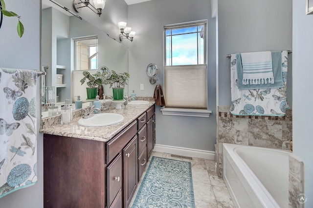 bathroom featuring vanity, tile patterned flooring, a wealth of natural light, and a tub