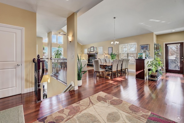 entrance foyer with lofted ceiling, a wealth of natural light, a notable chandelier, and dark hardwood / wood-style flooring