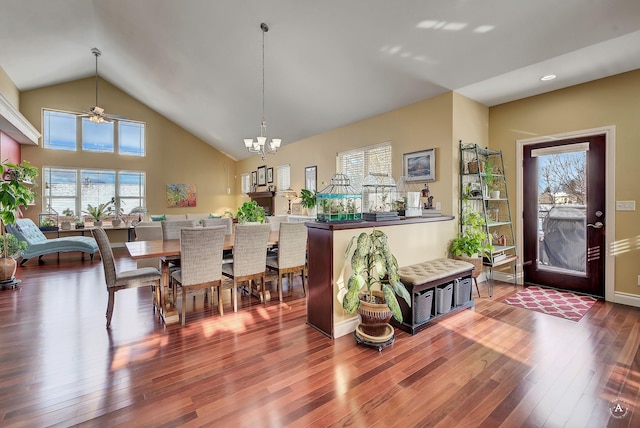 dining area featuring an inviting chandelier, wood-type flooring, and high vaulted ceiling