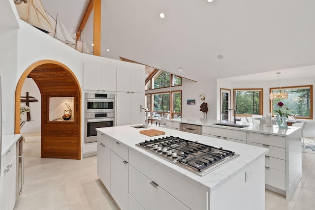 kitchen with appliances with stainless steel finishes, sink, a kitchen island with sink, and white cabinets