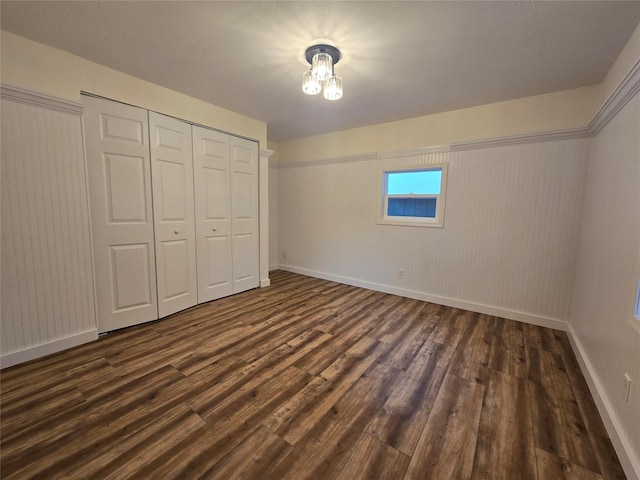 unfurnished bedroom with dark hardwood / wood-style flooring and a closet