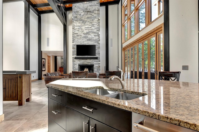 kitchen featuring light stone counters, sink, dishwasher, and a high ceiling