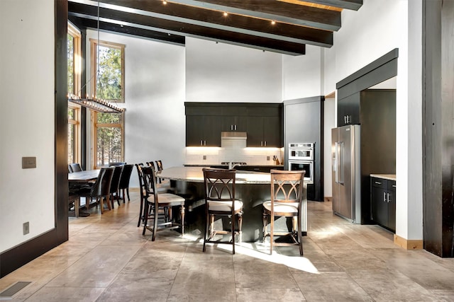 dining room with plenty of natural light, beamed ceiling, and a high ceiling