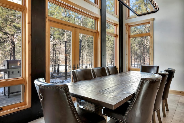 tiled dining space with a towering ceiling, a healthy amount of sunlight, and french doors