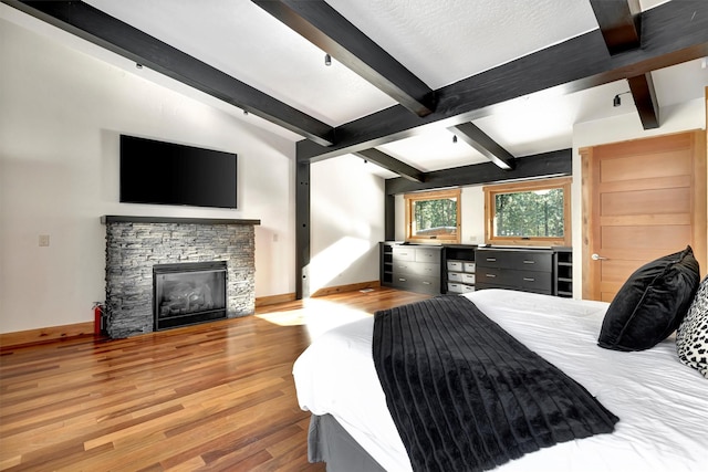 bedroom with a fireplace, light hardwood / wood-style flooring, and lofted ceiling with beams