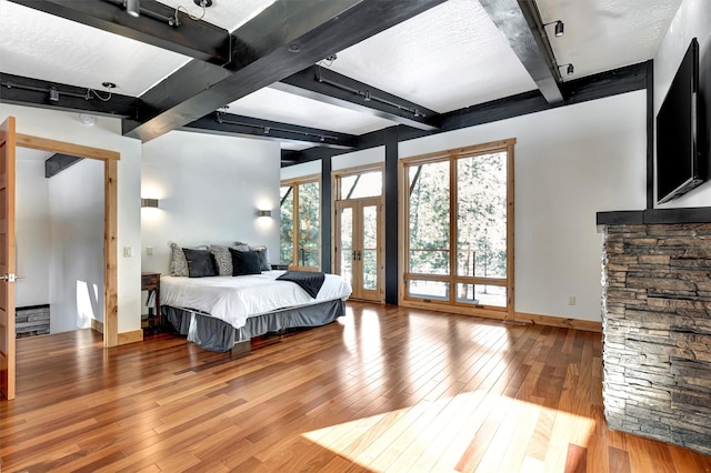 bedroom with hardwood / wood-style flooring, beam ceiling, and french doors