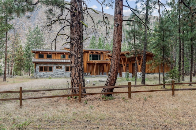 1180 Reardon Ln, Alberton, MT 59820 - view of front facade with a standing seam roof, stone siding, metal roof, fence, and a wooded view