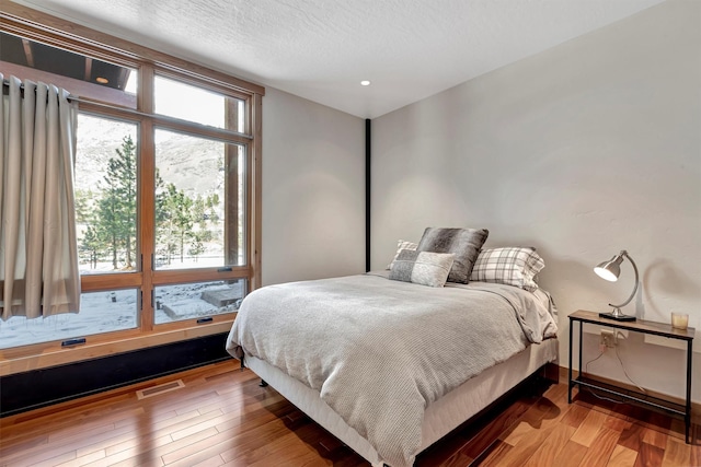 bedroom with wood-type flooring and a textured ceiling