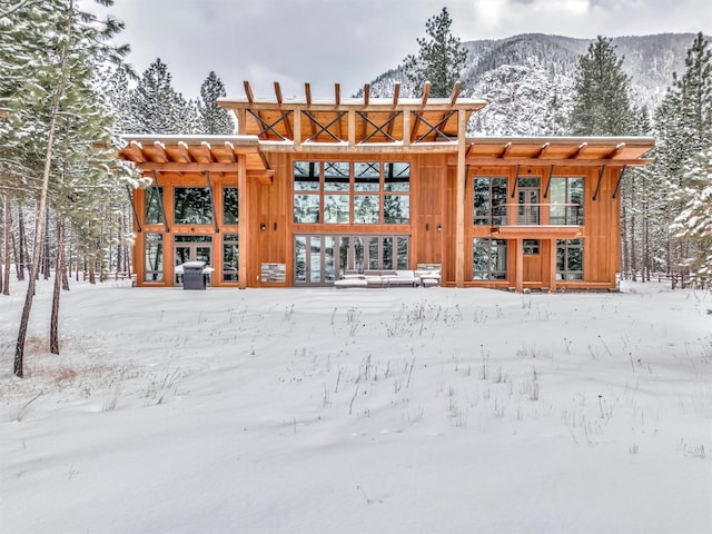 snow covered back of property featuring a mountain view and french doors