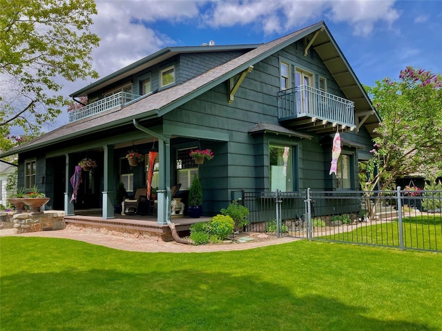 rear view of house featuring a balcony and a lawn