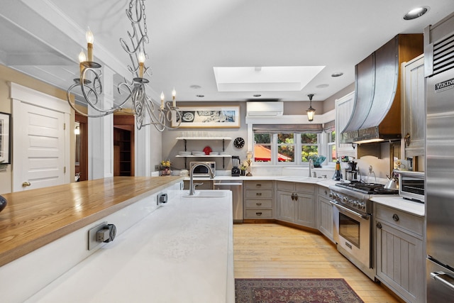 kitchen featuring premium range hood, sink, light hardwood / wood-style flooring, an AC wall unit, and premium appliances