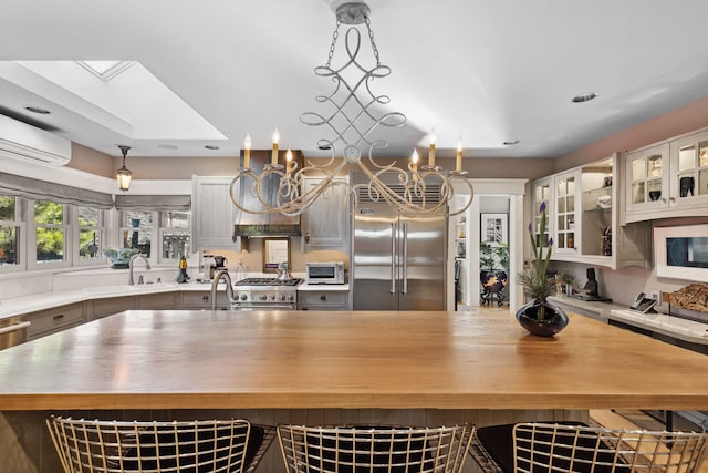 kitchen featuring sink, a wall mounted air conditioner, a skylight, high quality appliances, and pendant lighting