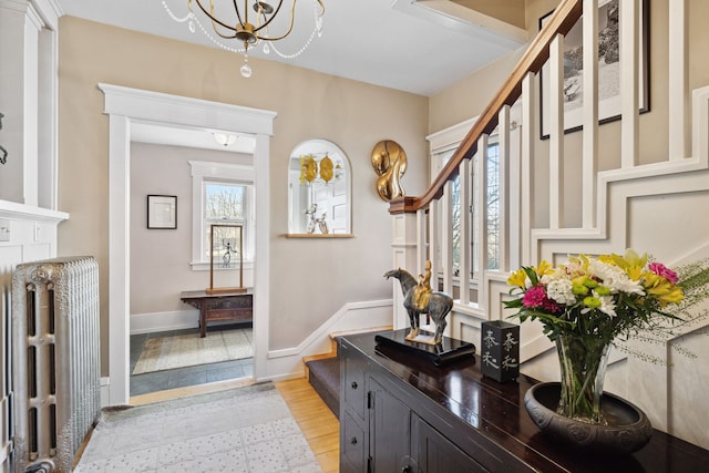 entrance foyer featuring radiator heating unit, an inviting chandelier, and light hardwood / wood-style flooring