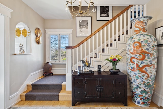 stairway with wood-type flooring and an inviting chandelier