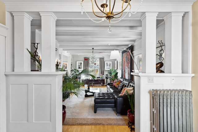 interior space with radiator, an inviting chandelier, beam ceiling, decorative columns, and light wood-type flooring